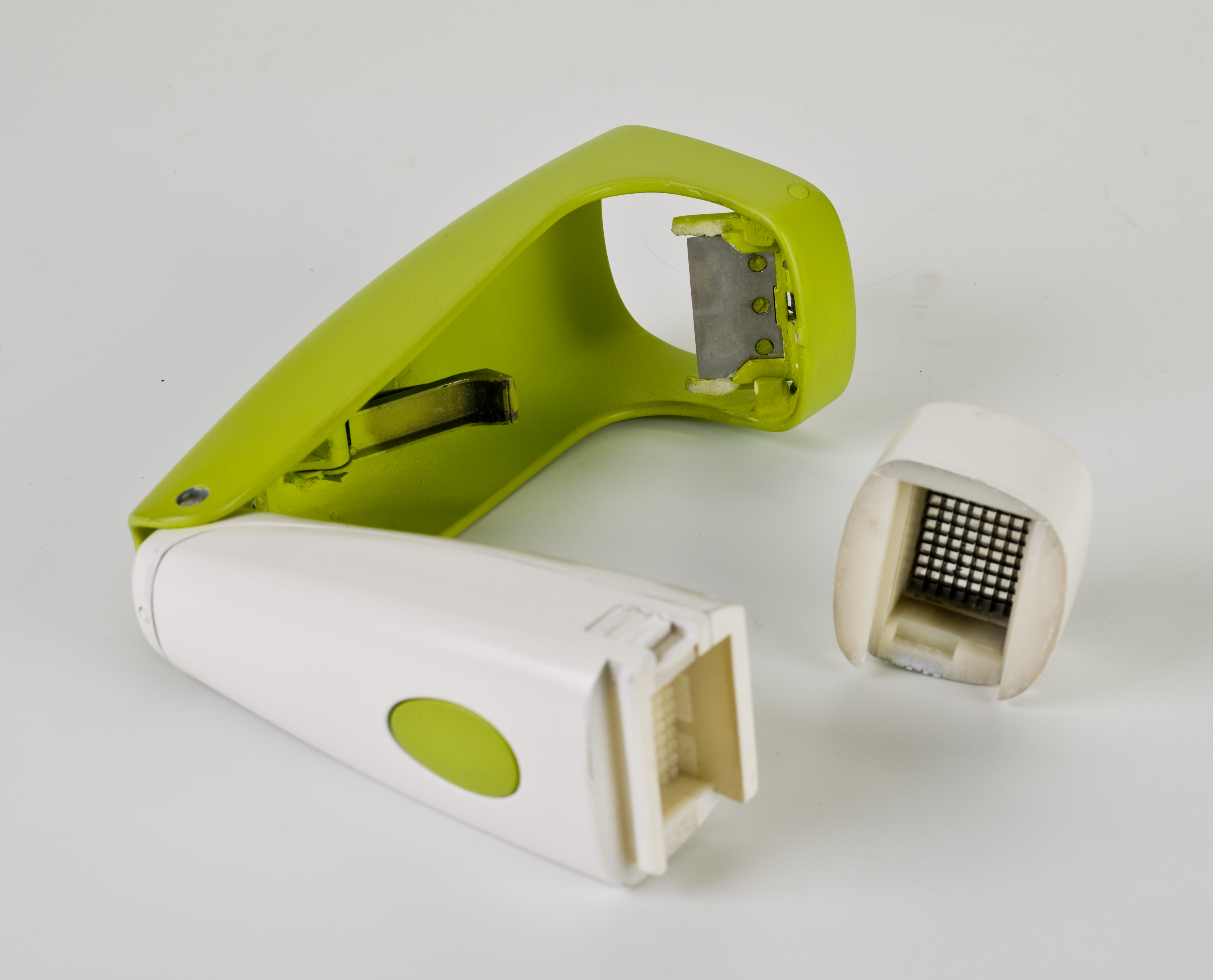 Disassembled green and white garlic mincer prototype