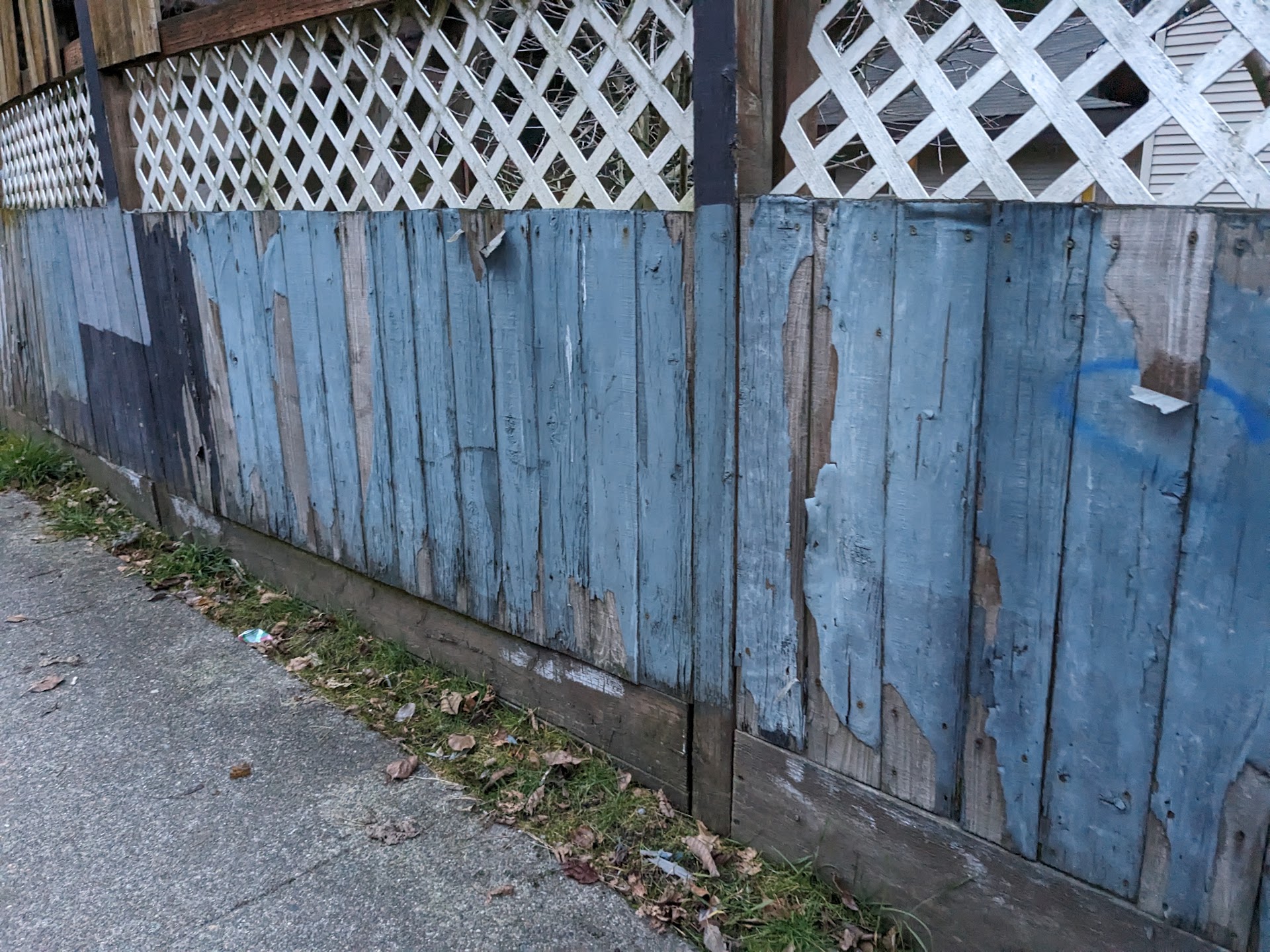 Weathered blue fence patched in uneven bands