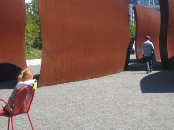 Child and distant figure framed by curved rust-colored walls